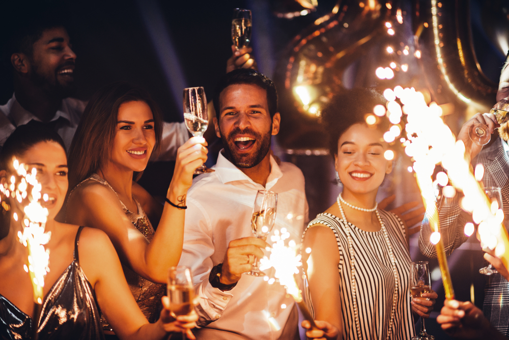 A group of three people celebrating with sparklers and champagne